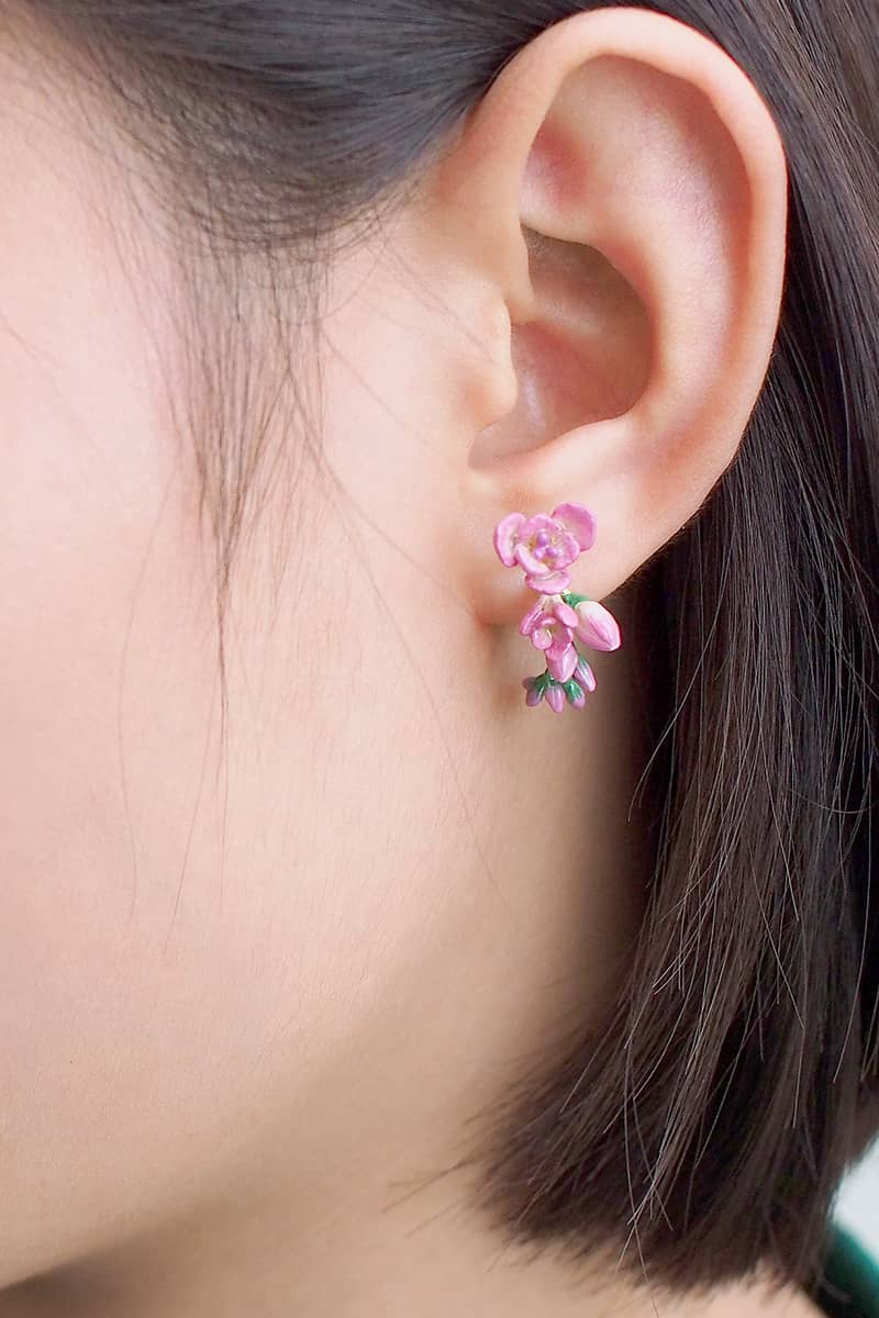 Close-up of pink flower earrings worn on a woman's ear