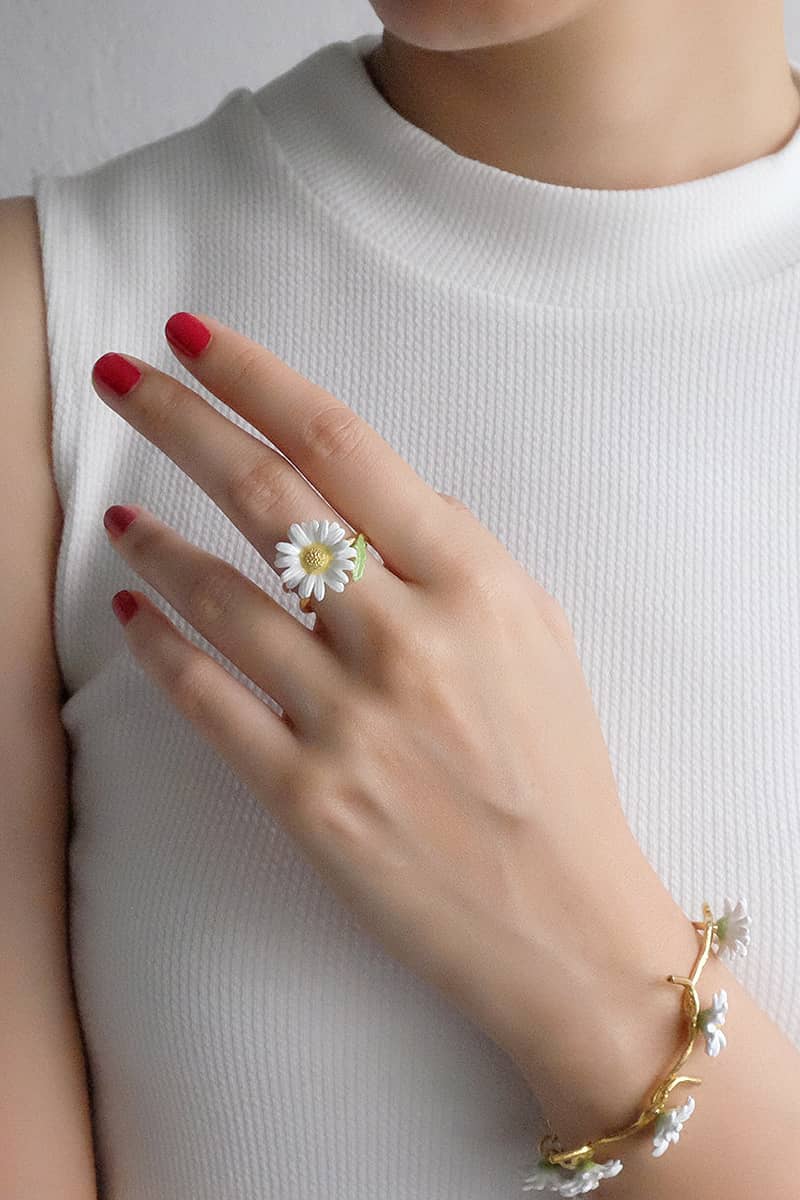 Close-up of a hand wearing a daisy ring and matching bracelet.