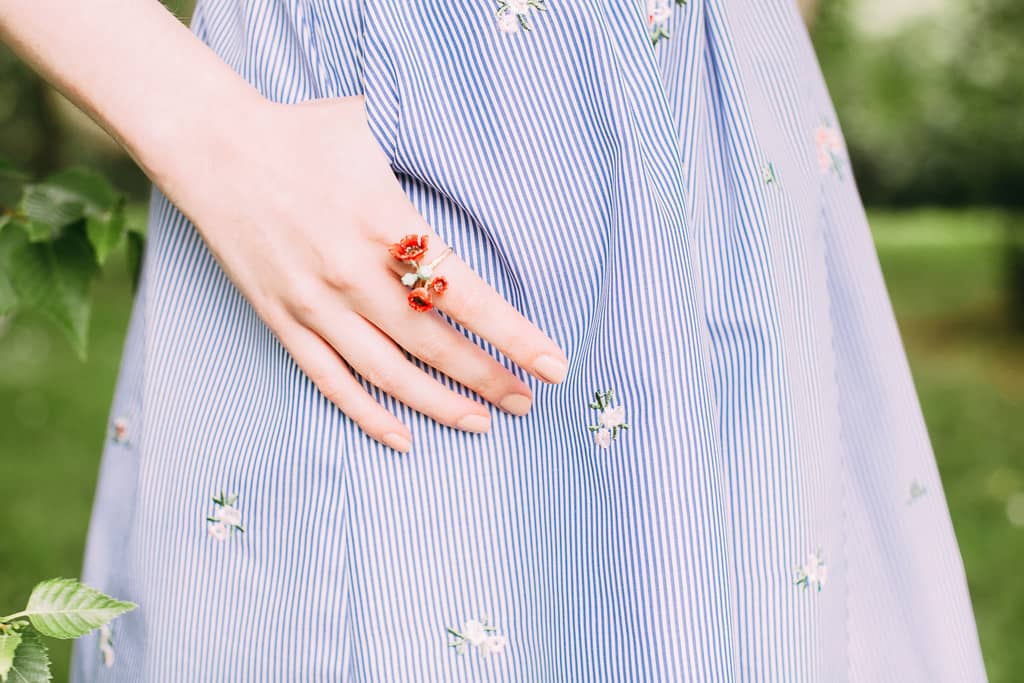 Close-up of a woman wearing a red poppy ring in a casual outfit