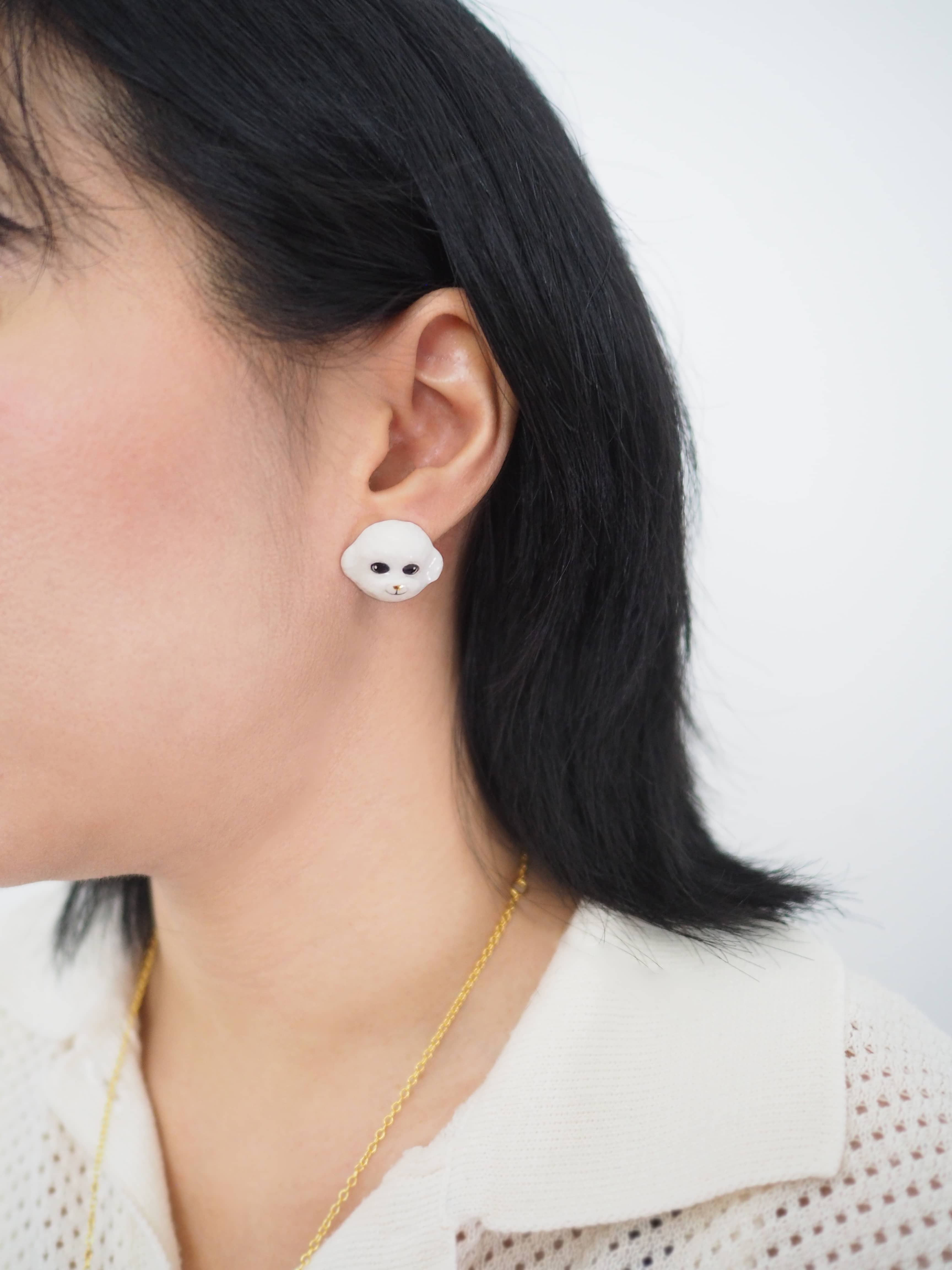 Handcrafted, cute poodle earrings worn on a model.
