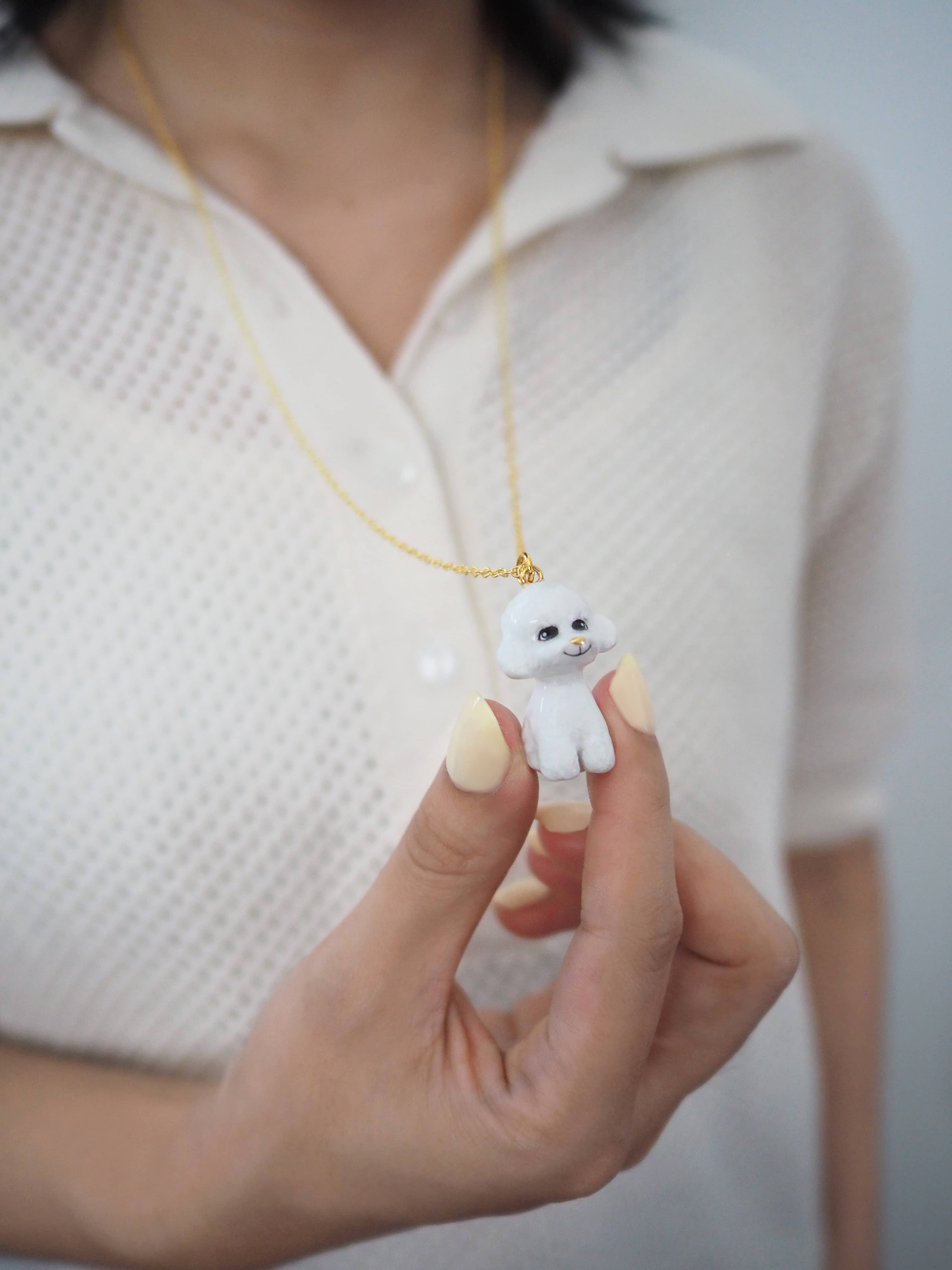 Adorable hand-painted poodle necklace worn by a model.