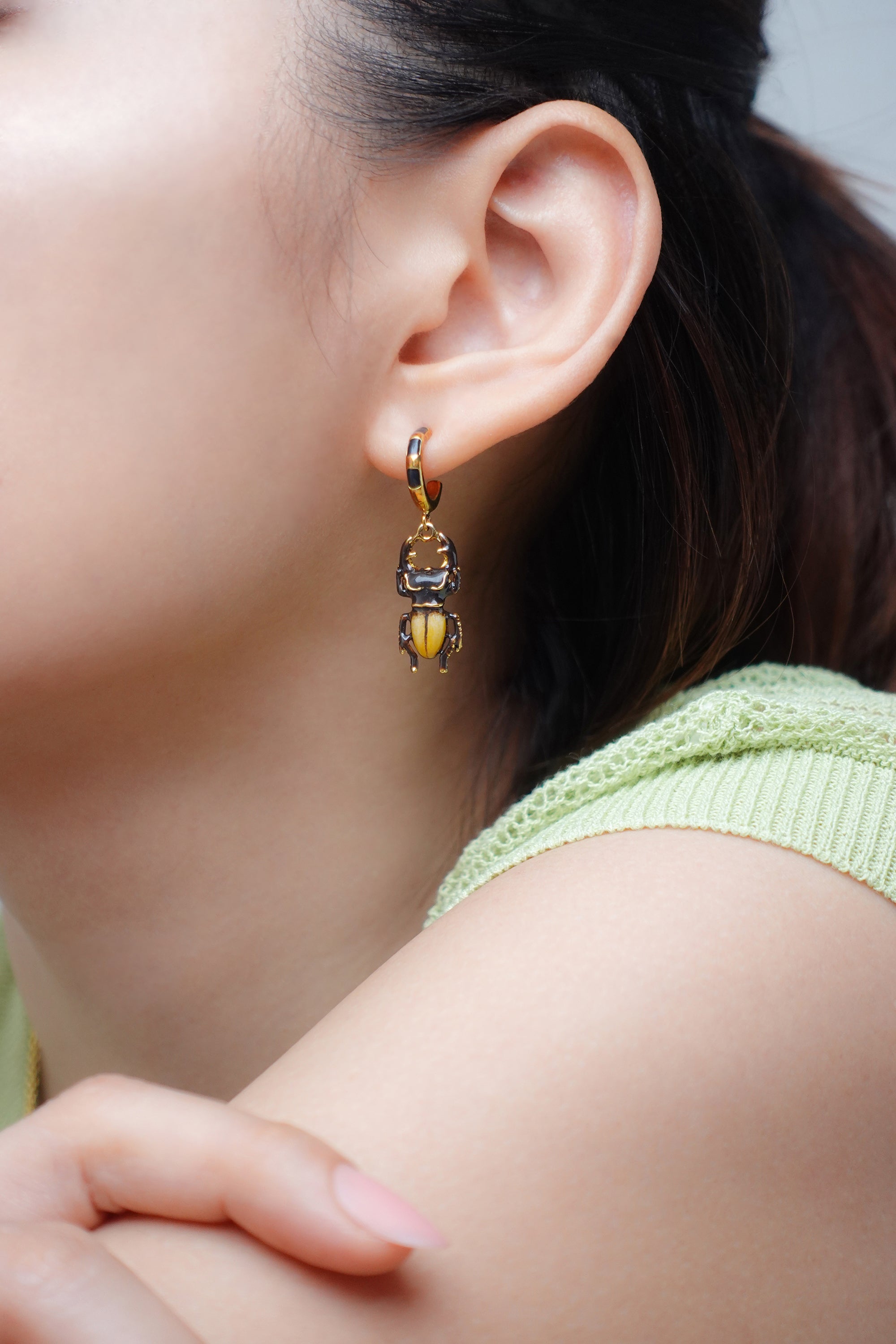 Close-up of a woman wearing stag beetle earrings with casual outfit, ideal for summer fashion.