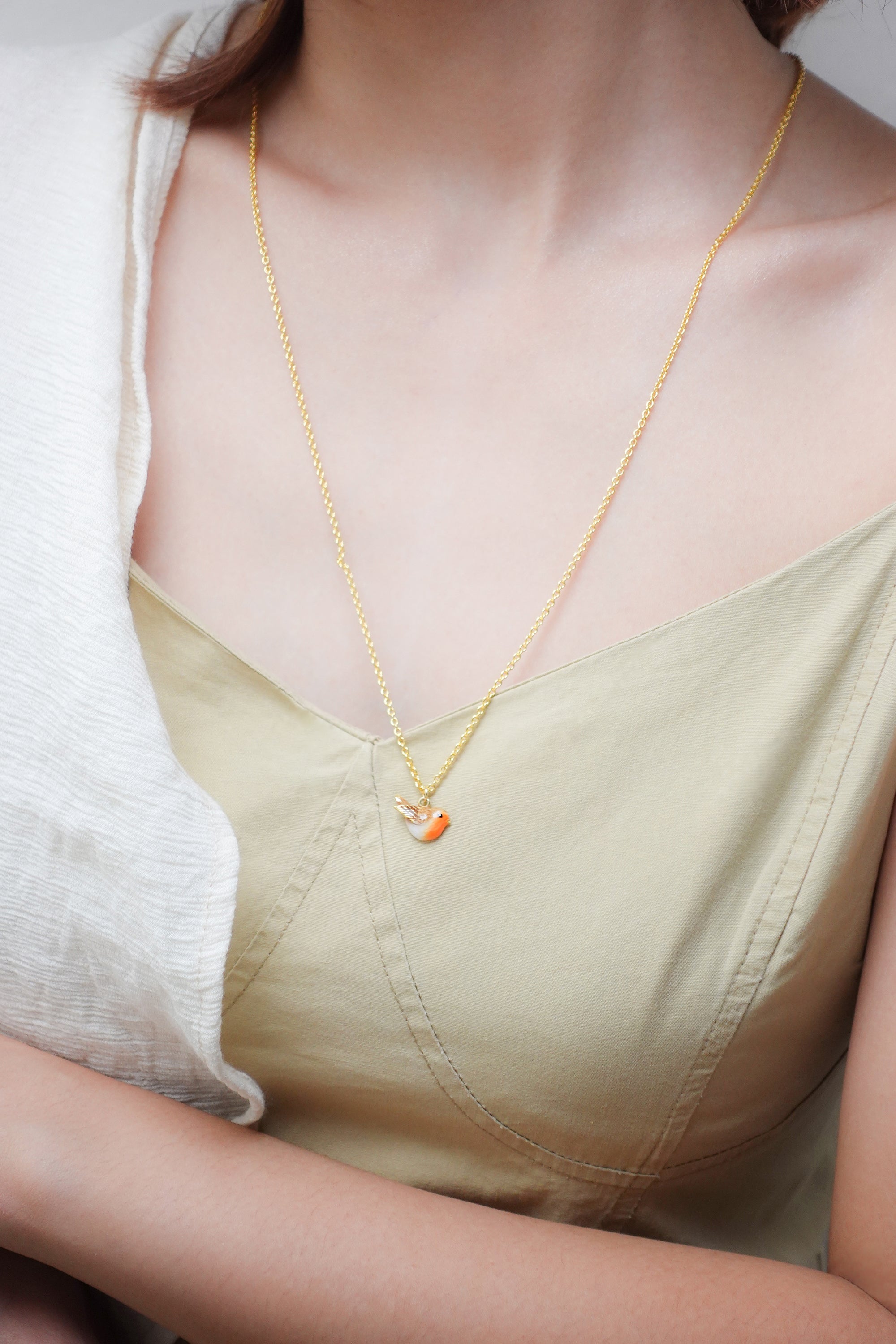 Delicate gold necklace featuring a bird pendant, showcased on a woman