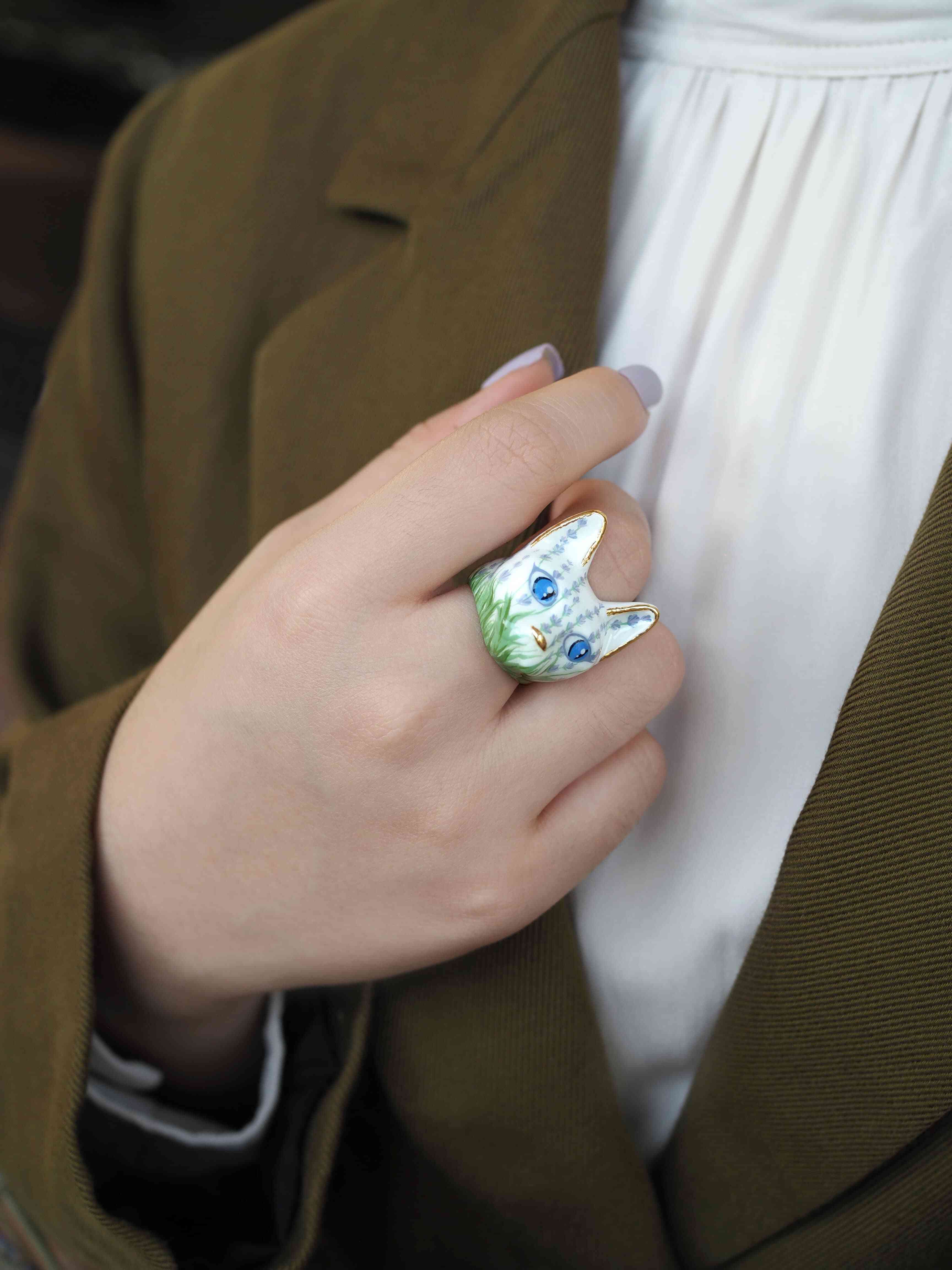 Close up of a hand adorned with an charming cat ring featuring floral pattern.