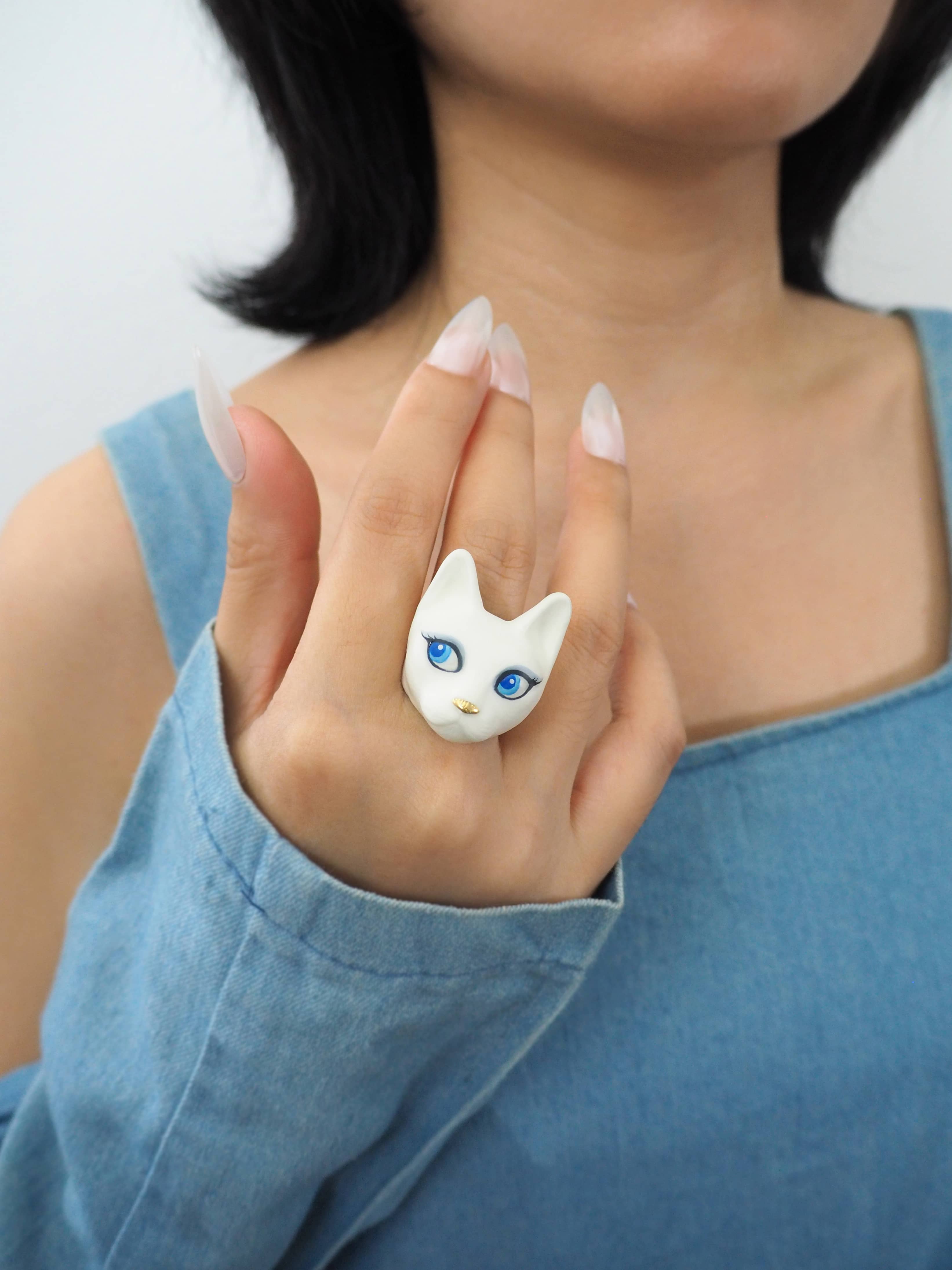 A unique hand-painted cat ring with charming blue eyes worn on a woman finger.