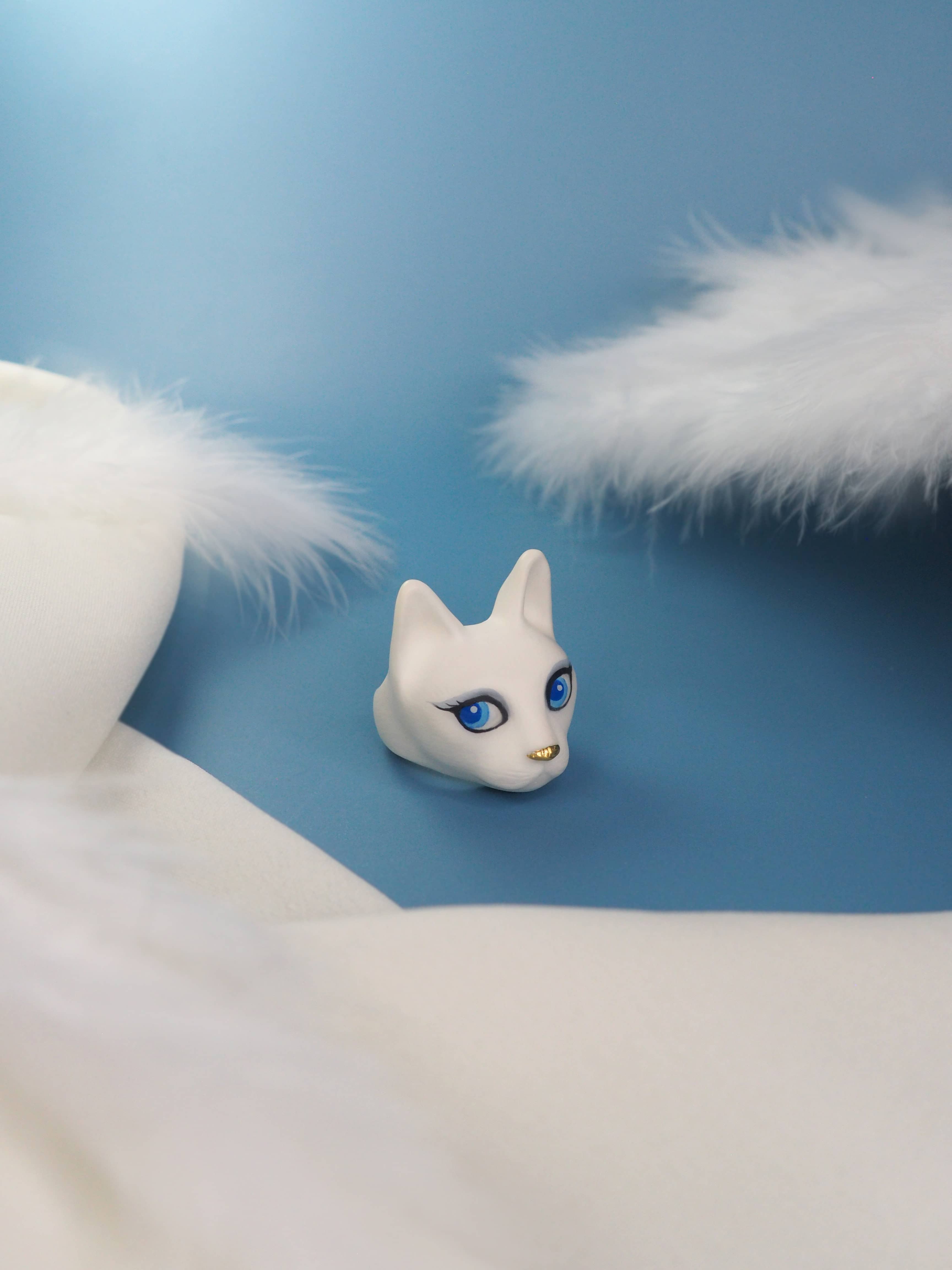 Beautiful white cat ring with captivating blue eyes placed on blue background with feather elements.