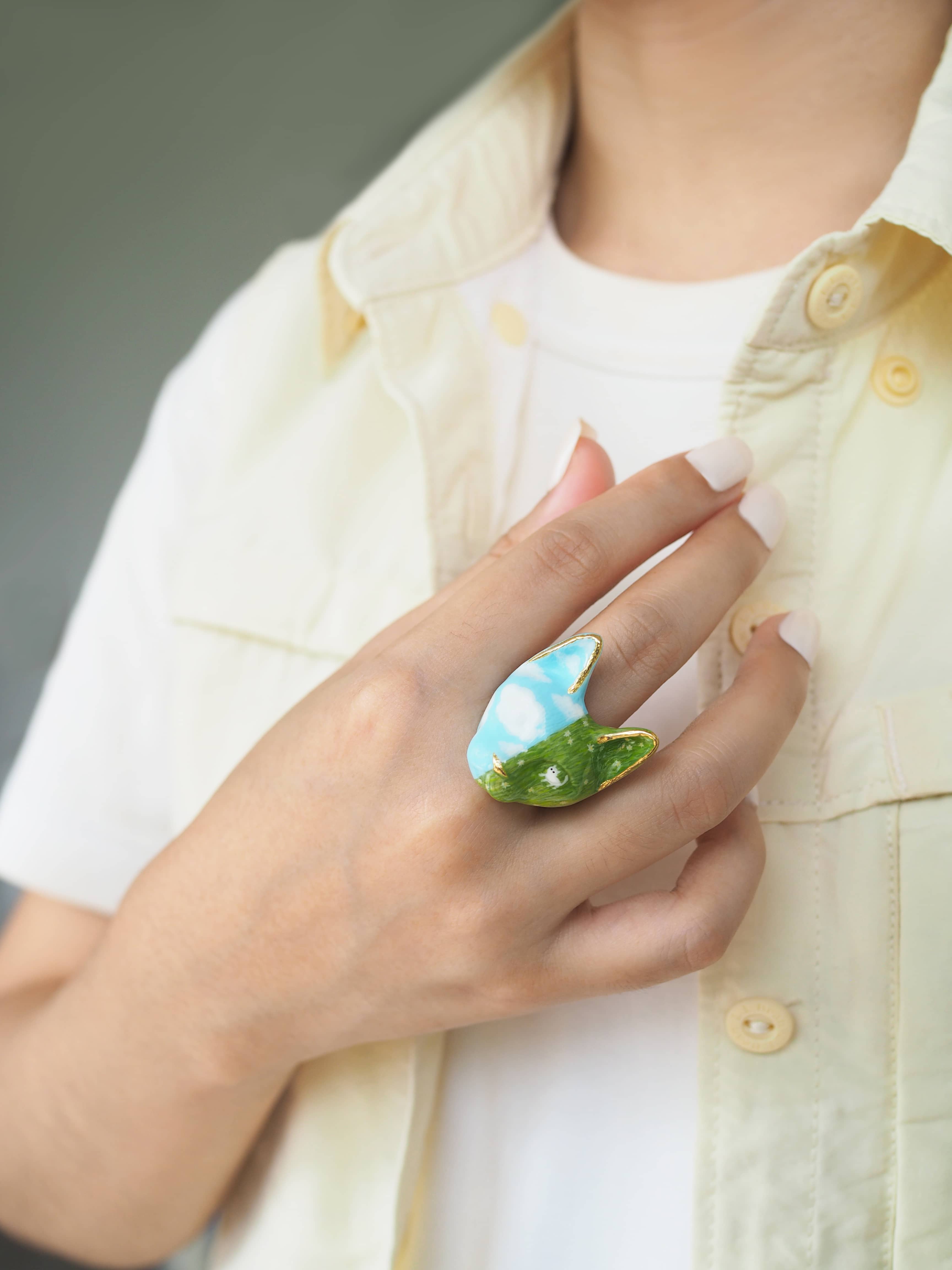  A beautifully hand-painted cat ring featuring vibrant colors worn on a hand