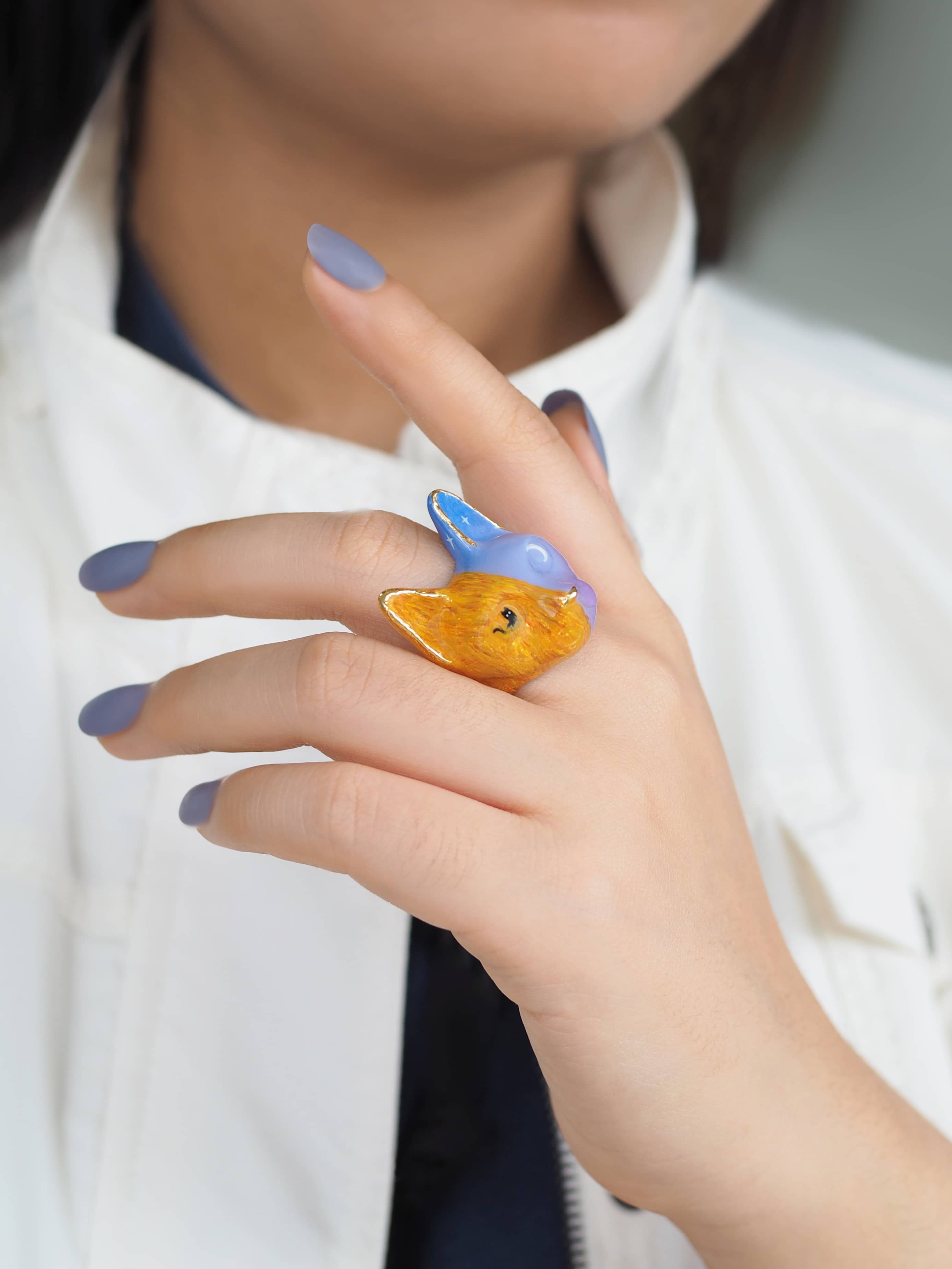 A beautifully hand-painted cat ring featuring vibrant colors worn on a hand