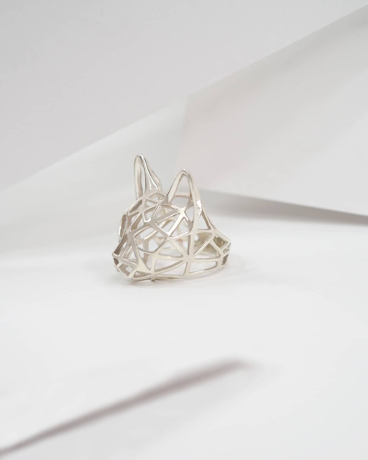 Unique silver cat ring placed on a hand a white background.