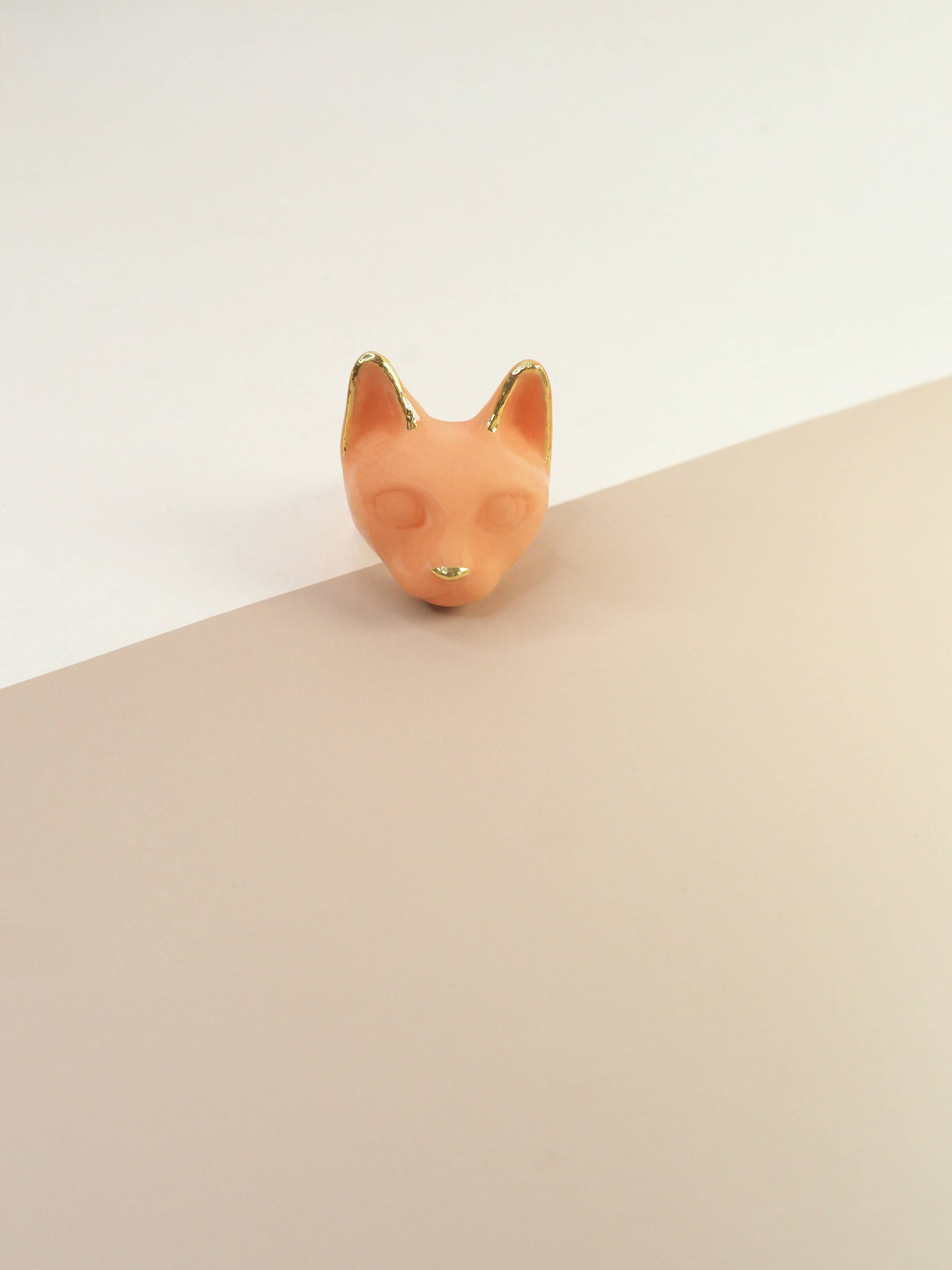 A orange cat's head ring with gold accents on the ears and a small gold nose