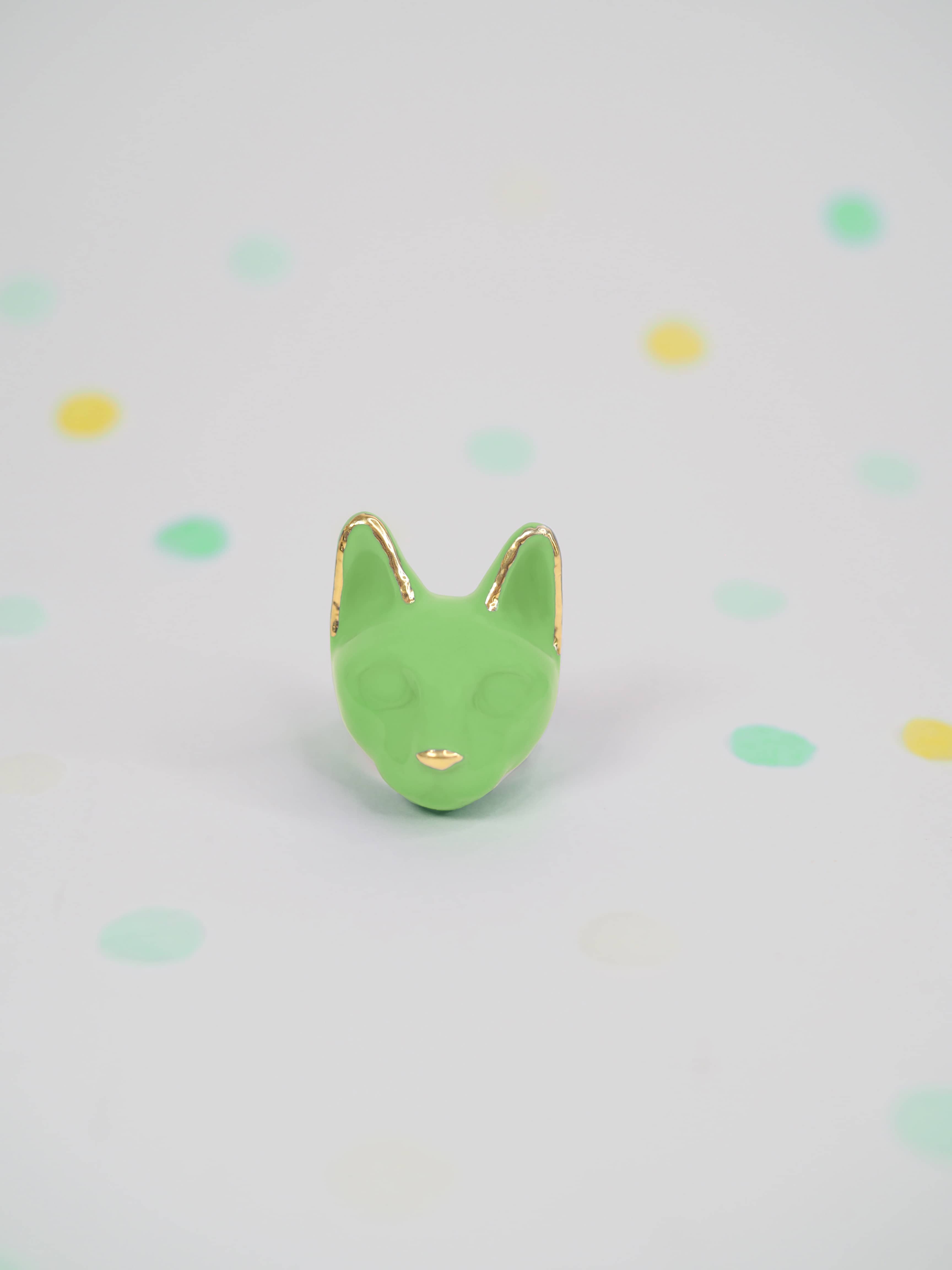 Vibrant green cat ring from the summer collection on a polka dot background.