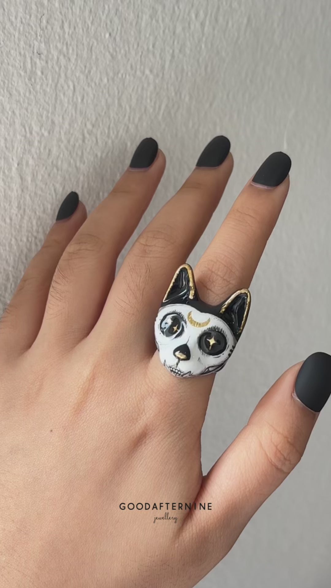 A hand showcasing two Halloween-themed cat rings with stunning designs