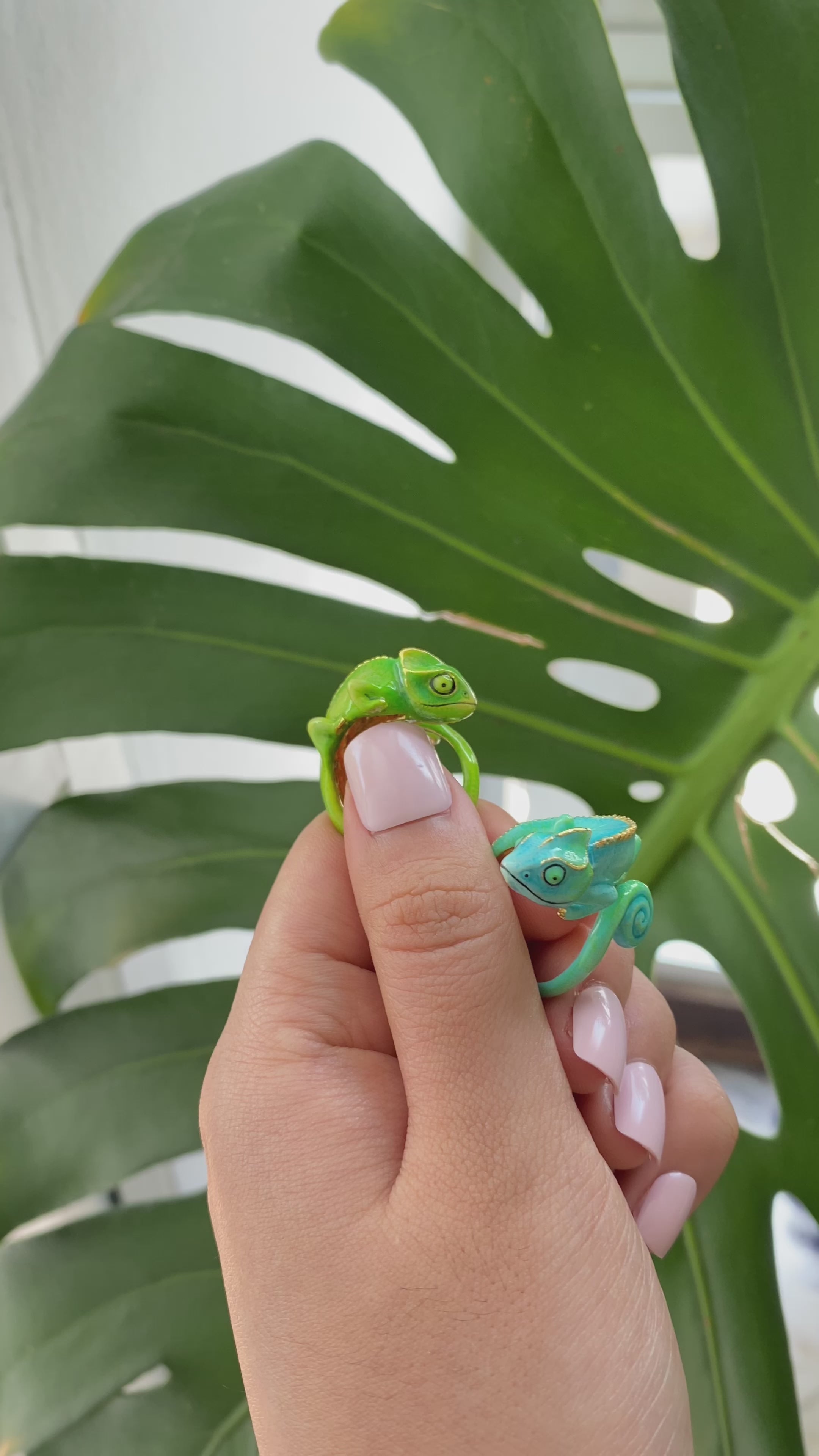 Handmade chameleon rings displayed on a finger surrounded by greenery.