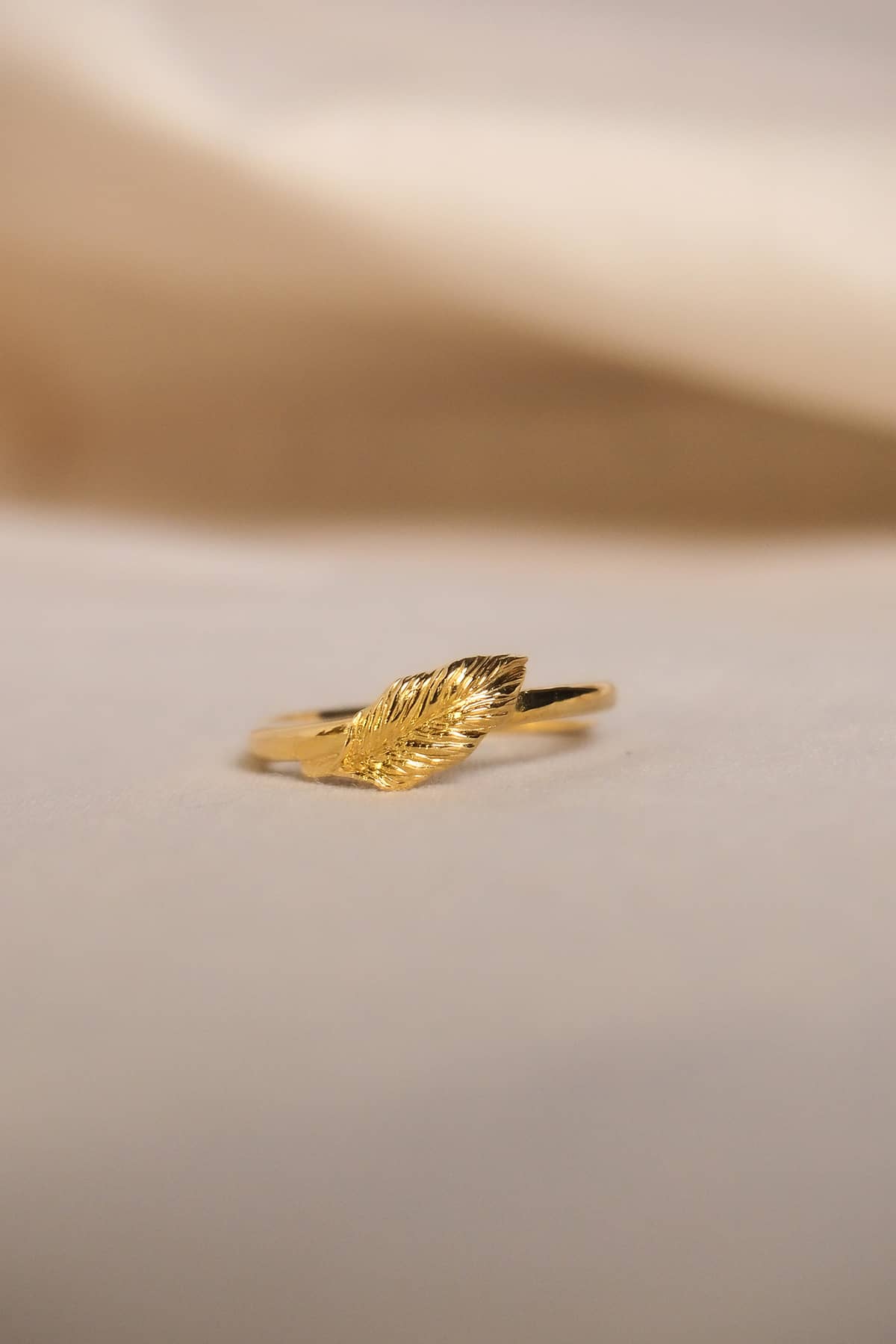 Minimalist gold ring with a stylish leaf detail on a soft background.