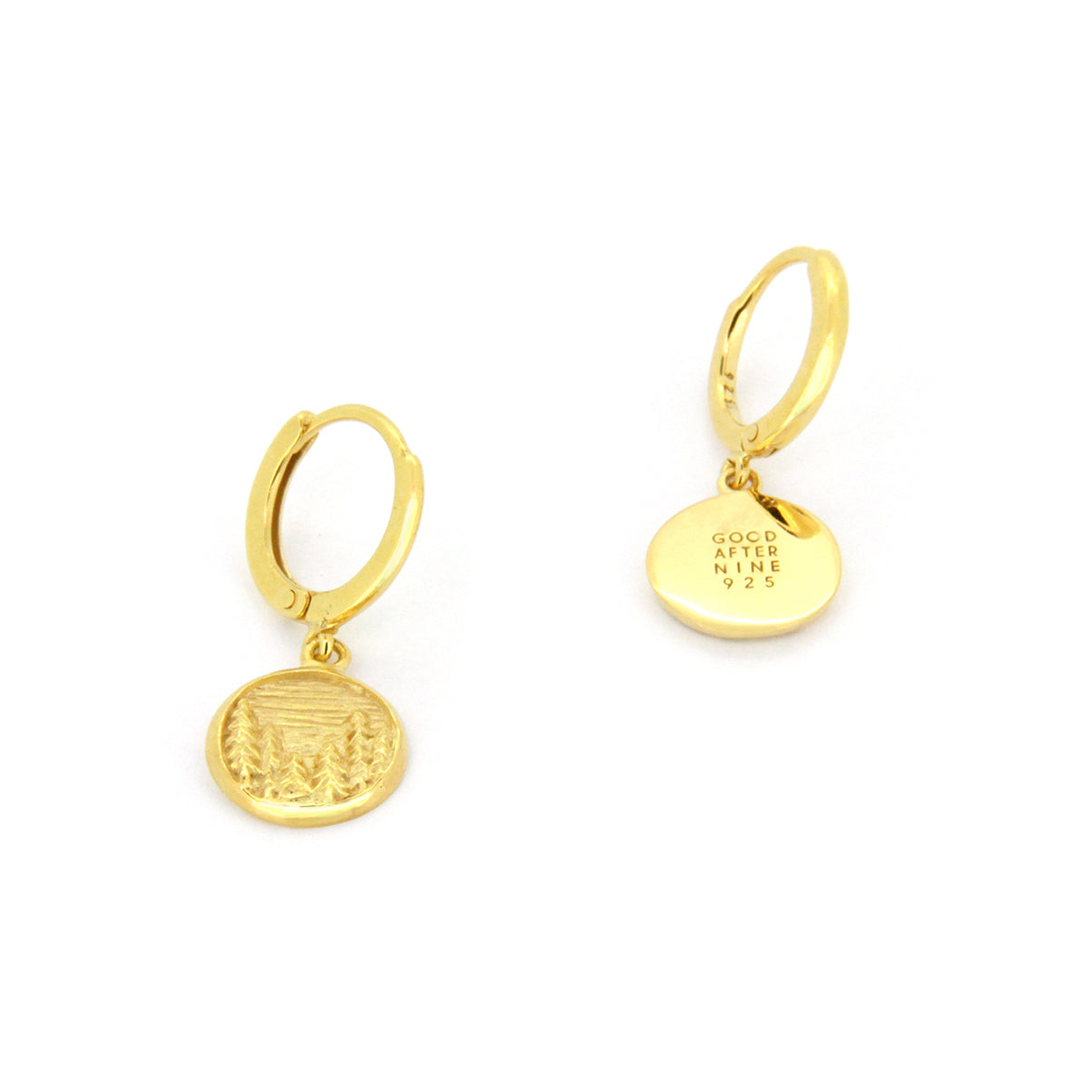 Charming gold earrings with circular pendants featuring detailed forest scene, showcasing trees and a landscape.