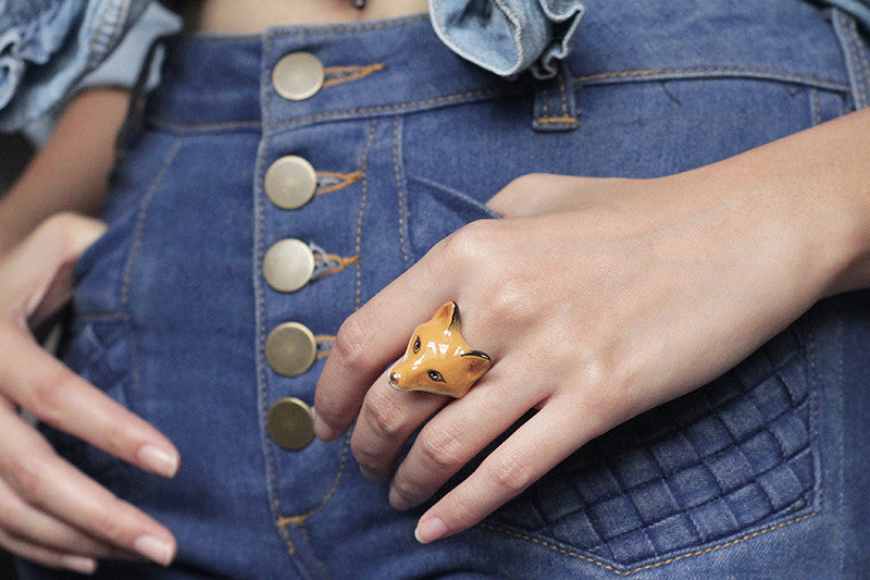 Close-up of a hand wearing a red fox ring with a denim outfit.