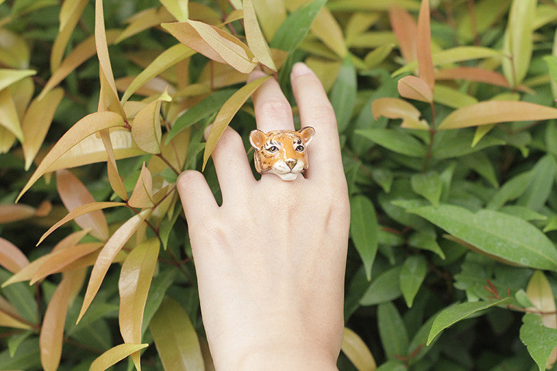Trendy tiger face ring showcased on a hand in a natural setting.