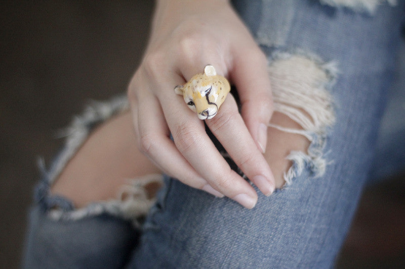 Close-up of an animal-inspired ring featuring a cheetah's face displayed on a casual outfit.