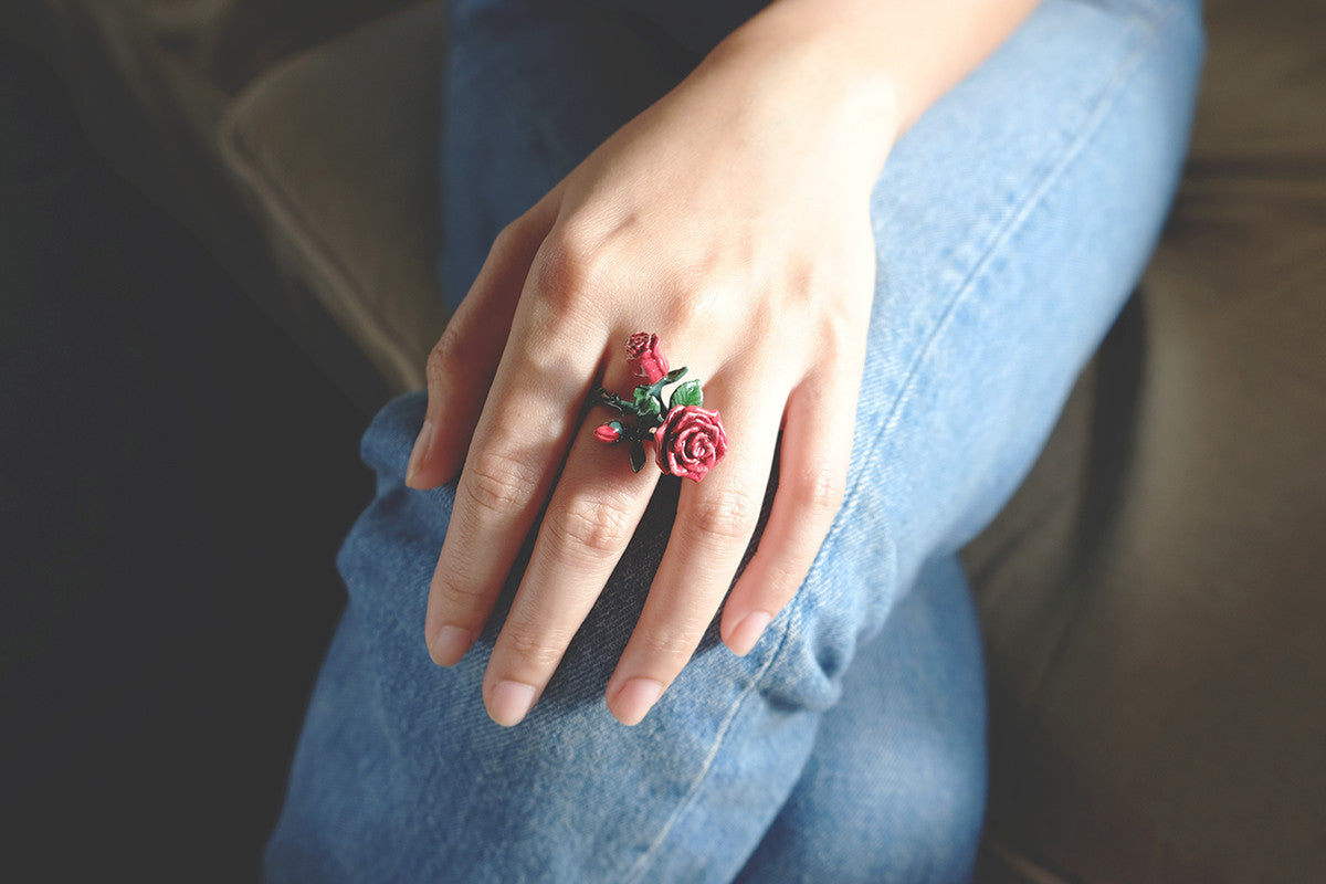 Close-up of a hand adorned with a red rose ring placed on a the person's knee