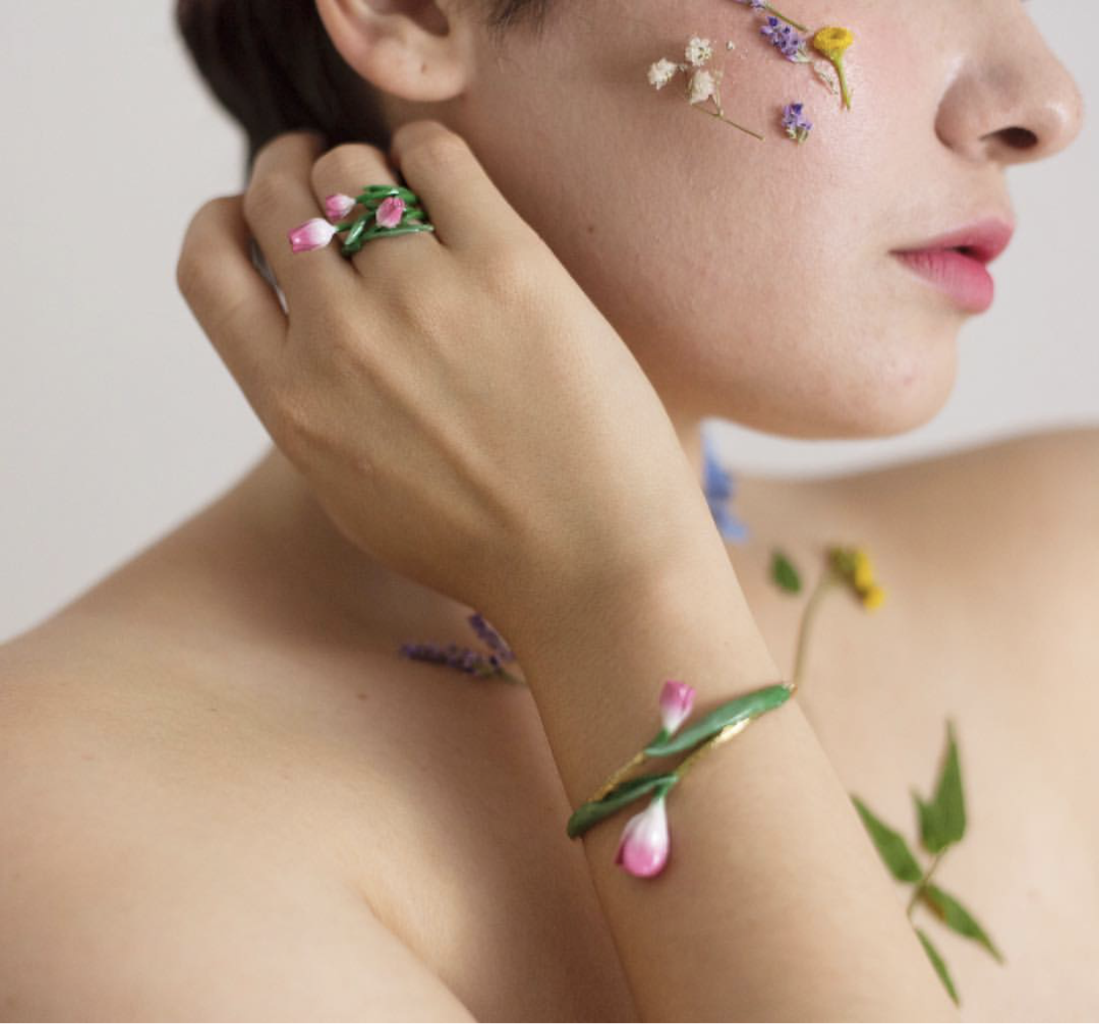 Tulip ring and bracelet adorn a model's arm, featuring delicate flowers on her skin.