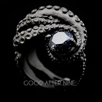 A silver octopus ring featuring a dark gemstone in the center, showcasing intricate tentacle details.