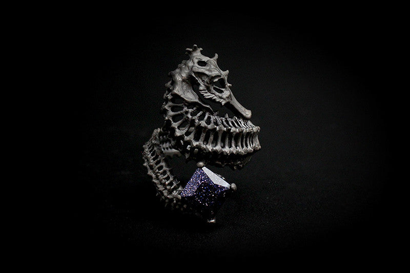 Handcrafted ring with a reef-inspired seahorse skeleton design and a purple gemstone.