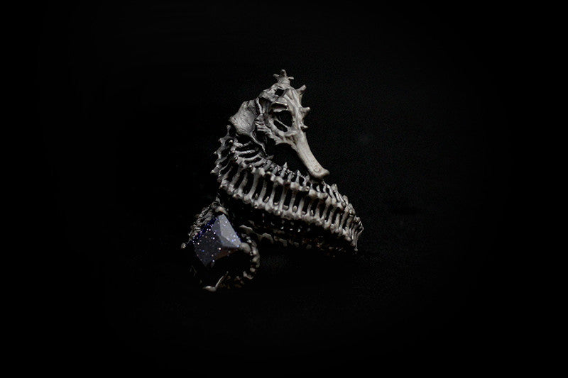 Unique ring designed with a reef-inspired seahorse skeleton and a shimmering purple gemstone.