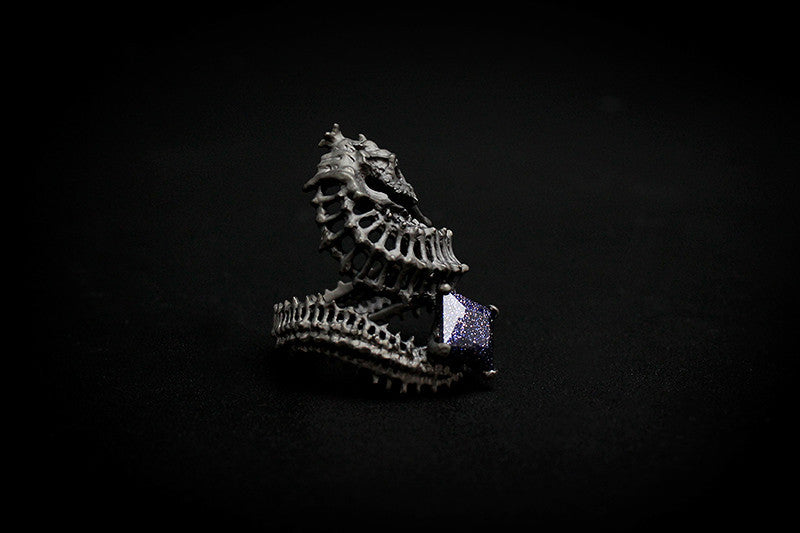 Handcrafted ring with a reef-inspired seahorse skeleton design and a purple gemstone.