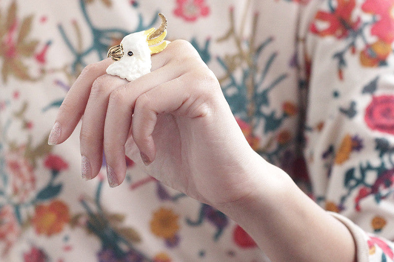 Close-up of a hand wearing a cockatoo ring with floral dress.