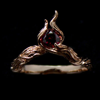Artisan-crafted rose gold ring showcasing a flame design with a gemstone.