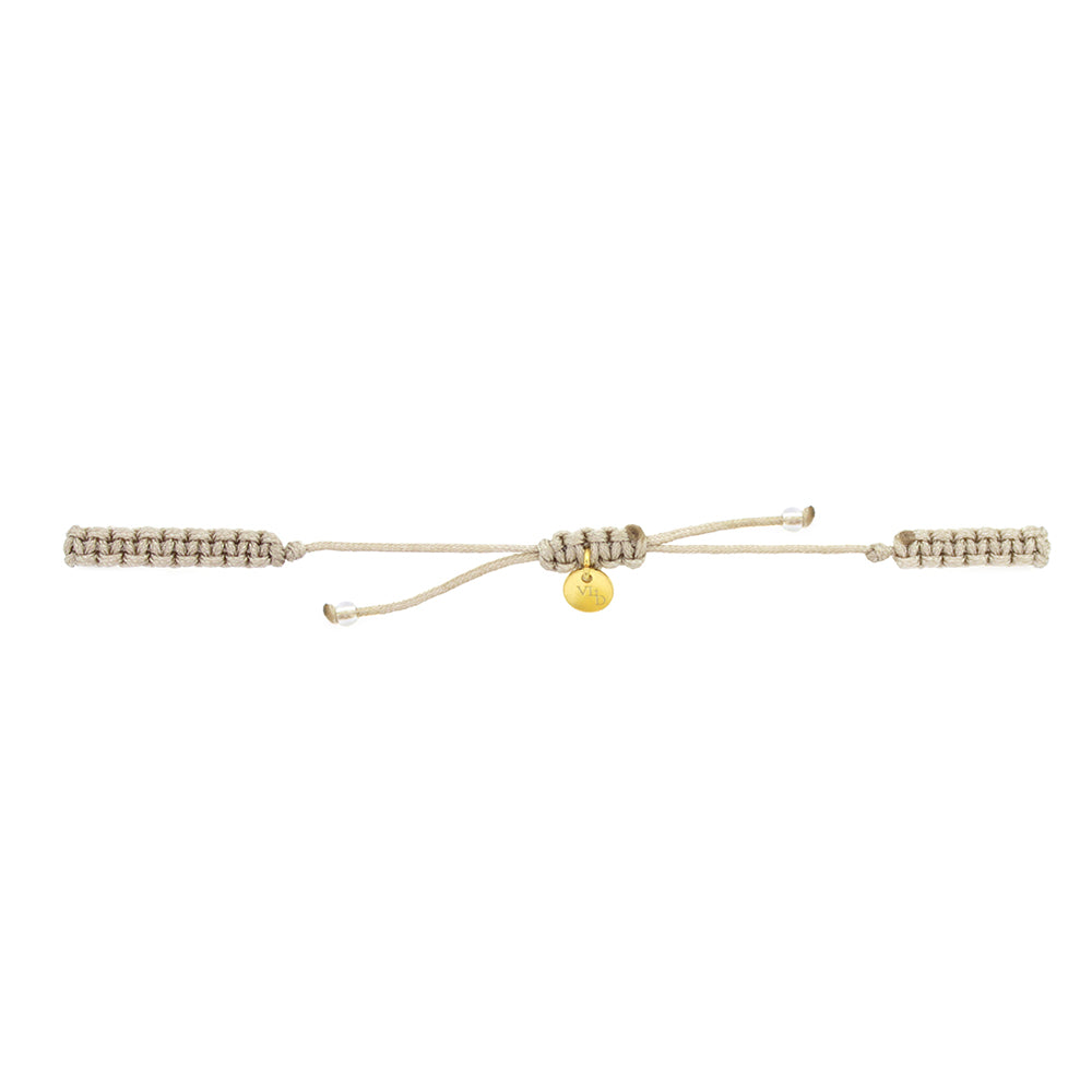 A gold Trimurti Vishnu charm and a gold Garuda charm on a beige bracelet with grey quartz stone.