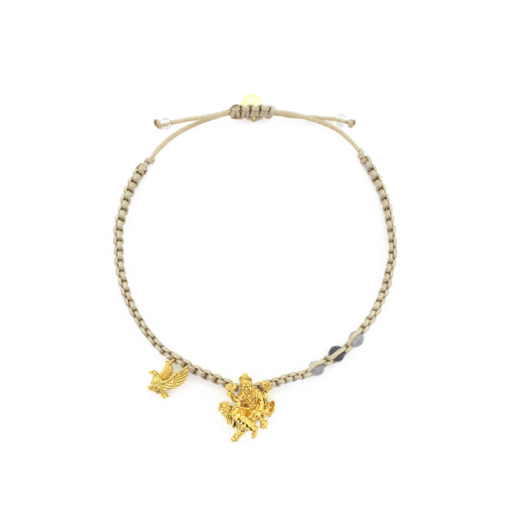 A gold Trimurti Vishnu charm and a gold Garuda charm on a beige bracelet with grey quartz stone.