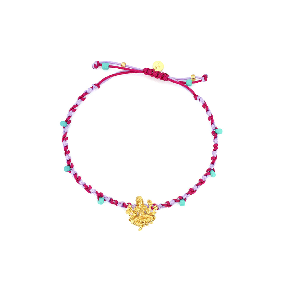 A bracelet in purple and  pink, and turquoise sand beads, featuring a gold Parvati charm