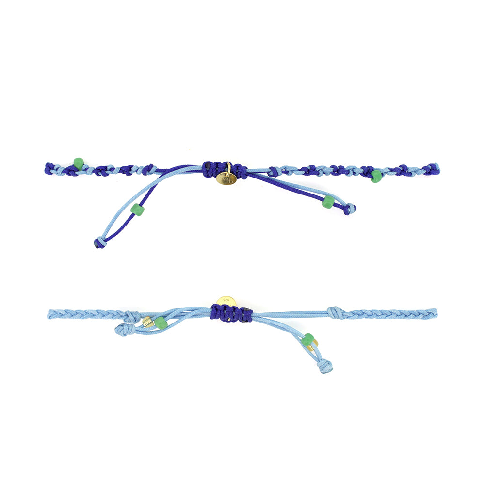 Two colorful bracelets in blue threads with blue and green beads, featuring a gold Trimurti Shiva charm and a gold Nandi charm.