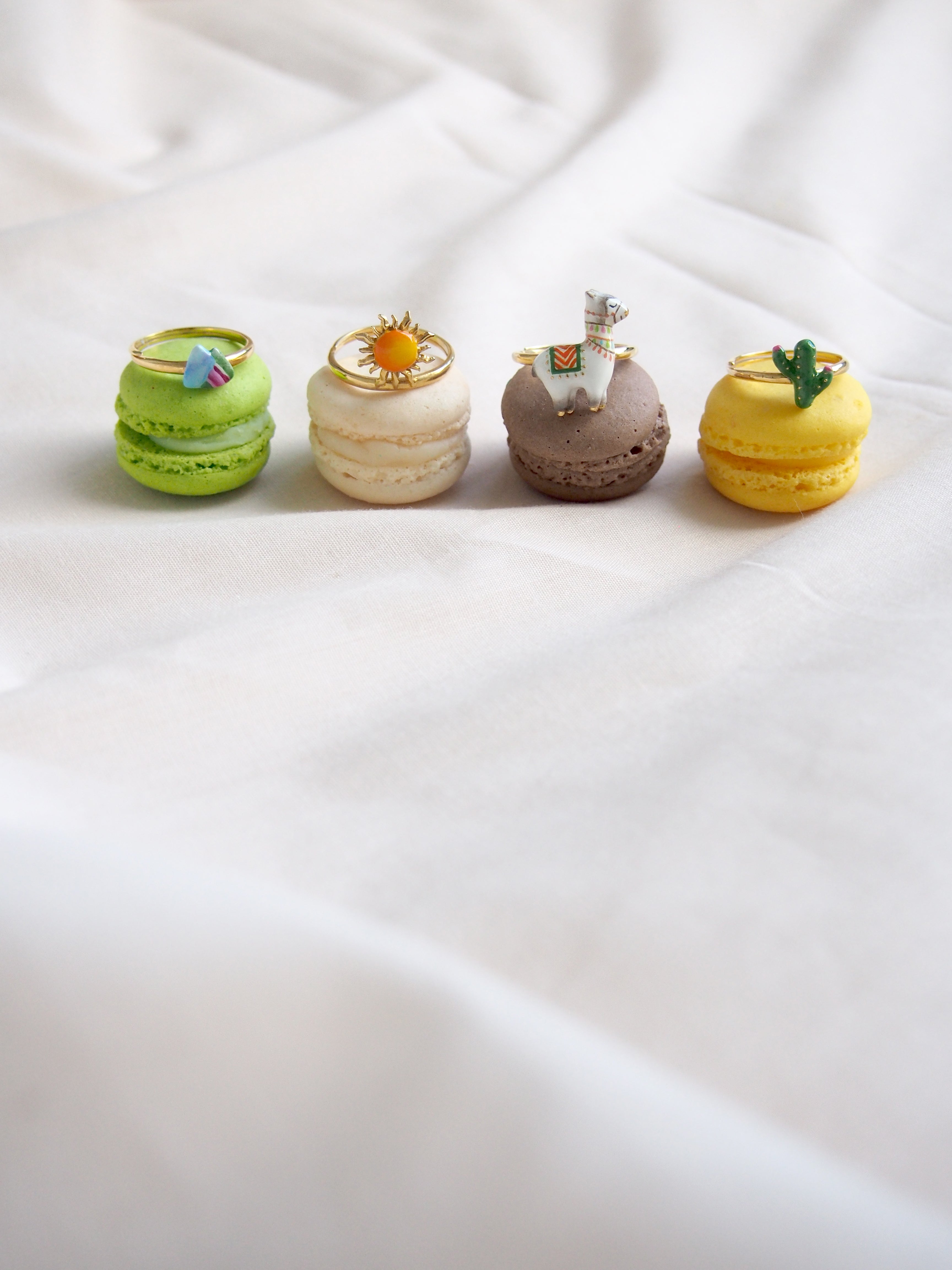 Playful stacking ring set featuring a mountain, sun, alpaca, and cactus design placed on colorful macarons.